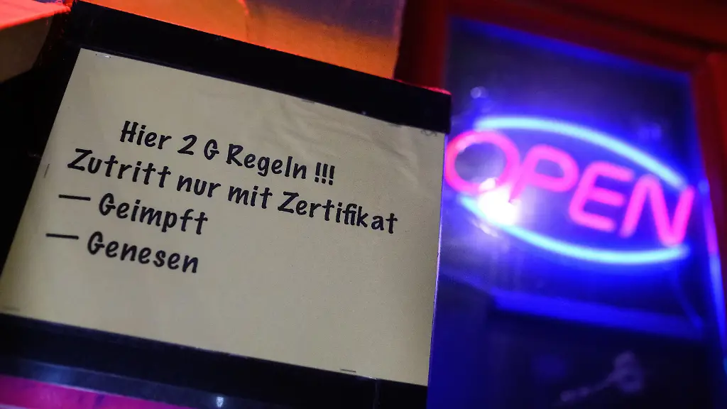 Hier-2G-Regeln-Zutritt-nur-mit-Zertifikat-Geimpft-Genesen-steht-auf-einem-Zettel-am-Eingangs-eines-Lokals-in-St-Pauli-neben-einem-Open-Leuchtschild-Ungeimpfte-werden-ab-dem-20-November-in-Hamburg-grossteils-aus-dem-oeffentlichen-Leben-ausgeschlossen-Demnach-gilt-nun-eine-2G-Pflicht-Zugang-nur-fuer-Geimpfte-und-Genesene-unter-anderem-fuer-Gastronomie-Bars-Clubs-Discos-und-koerpernahe-Dienstleister