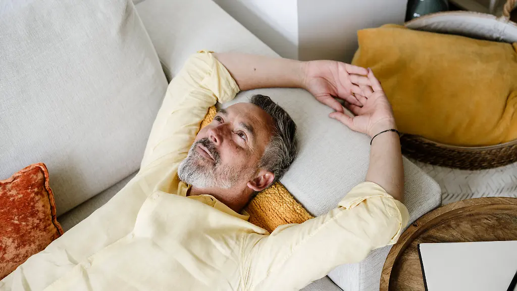 Mature-person-relaxing-and-daydreaming-on-sofa-at-home-indoors-model-released-Symbolfoto-property-released-KNSF12075