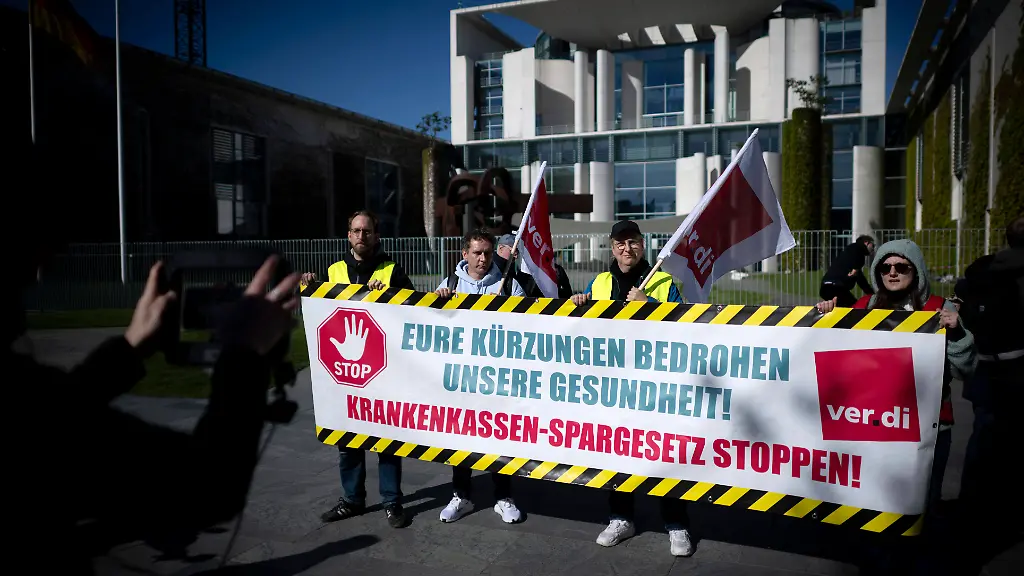 Protest-gegen-Gesundheitsreform-DEU-Deutschland-Germany-Berlin-29-04-2026-Demonstranten-mit-Transparent-Eure-Kuerzungen-bedrohen-unsere-Gesundheit-der-Gewerkschaft-verdi-Initiativen-aus-dem-Gesundheitswesen-und-Medizinisches-Personal-beim-Protest-gegen-das-geplante-Sparpaket-fuer-die-Krankenkassen-und-die-geplante-Reform-des-deutschen-Gesundheitssystems-und-der-gesetzlichen-Krankenversicherung-welches-vom-Bundeskabinett-beschlossen-werden-soll-anlaesslich-der-Kabinettssitzung-vor-dem-Bundeskanzkleramt-in-Berlin-Deutschland