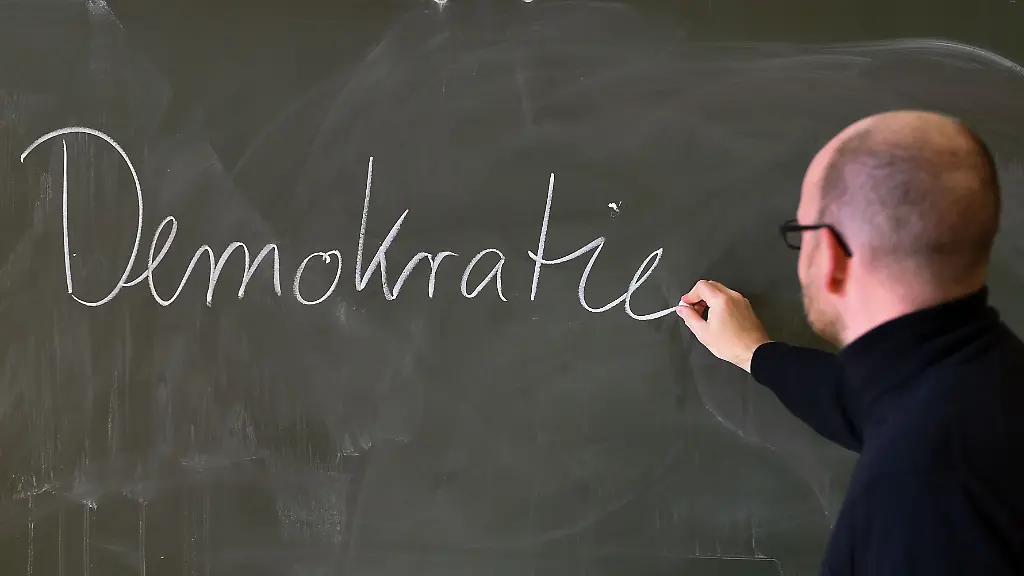 Andreas-Steiner-Schulleiter-der-Fichtenberg-Oberschule-im-Berliner-Steglitz-schreibt-an-der-Tafel-das-Wort-Demokratie