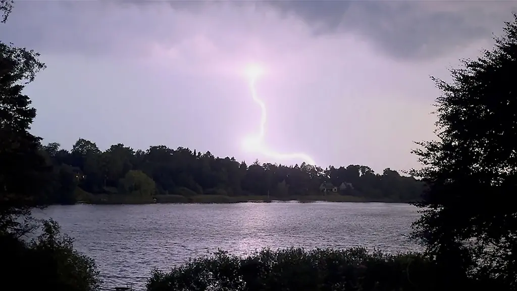 Ein-Blitz-zuckt-waehrend-eines-Unwetters-ueber-dem-Langsee-in-der-Naehe-von-Eckernfoerde-Nach-den-hochsommerlichen-Temperaturen-vom-Tag-hat-ein-Gewitter-mit-Starkregen-und-Sturm-am-Abend-fuer-Abkuehlung-gesorgt