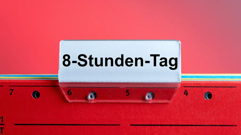 M-Eine-symbolische-rote-Haengeregistermappe-inkl-Sichtreiter-mit-der-Aufschrift-8-Stunden-Tag-vor-einem-roten-Hintergrund-Foto-mit-Composing-als-Symbolbild-fuer-die-Debatte-einer-Wochenarbeitszeit-ohne-eine-Begrenzung-der-taeglichen-Arbeitszeit-Aktuell-ist-der-Acht-Stunden-Arbeitstag-im-Arbeitszeitgesetz-ArbZG-festgeschrieben-Die-Merz-Regierung-plant-dies-mit-einer-Wochenarbeitszeit-flexibler-zu-gestalten