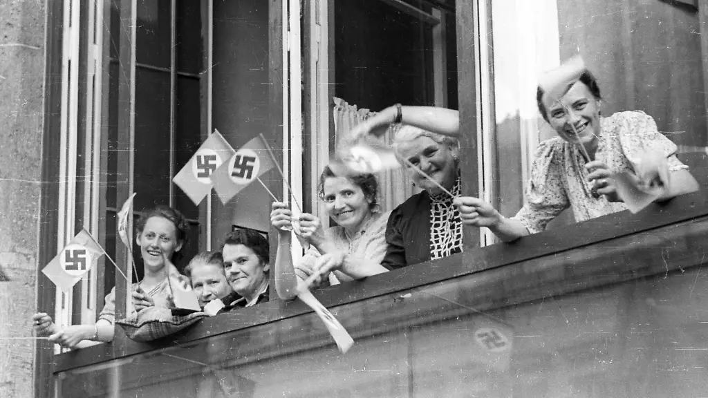 Reichsparteitag-der-NSDAP-1935-in-Berlin-Frauen-mit-Hakenkreuzfaehnchen-stehen-am-Fenster-und-warten-dass-der-Fuehrertross-vorbeikommt-14-09