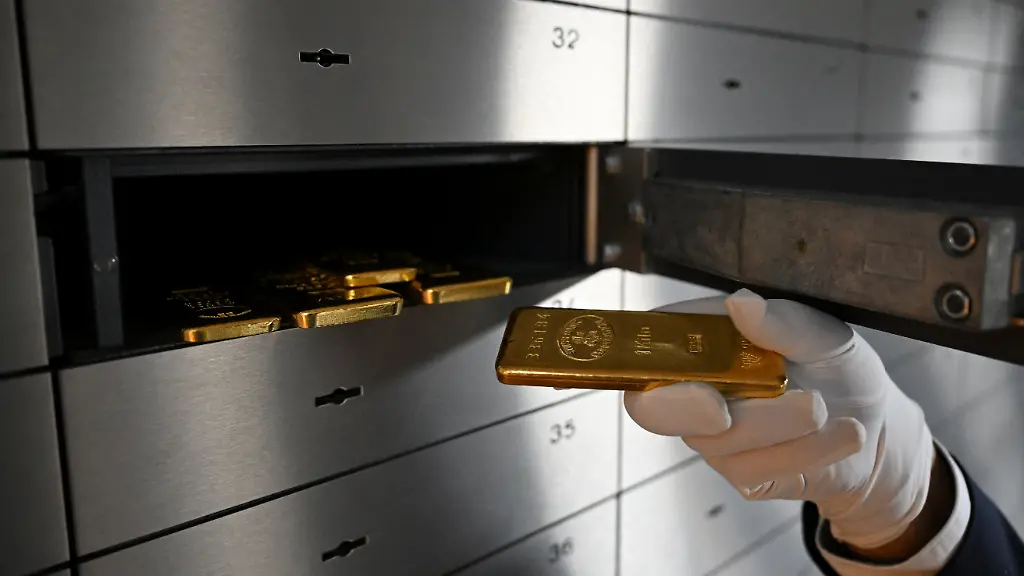 An-employee-handles-a-gold-bar-as-bars-of-various-values-are-stored-in-a-safe-deposit-room-in-Munich-Germany-January-28-2026