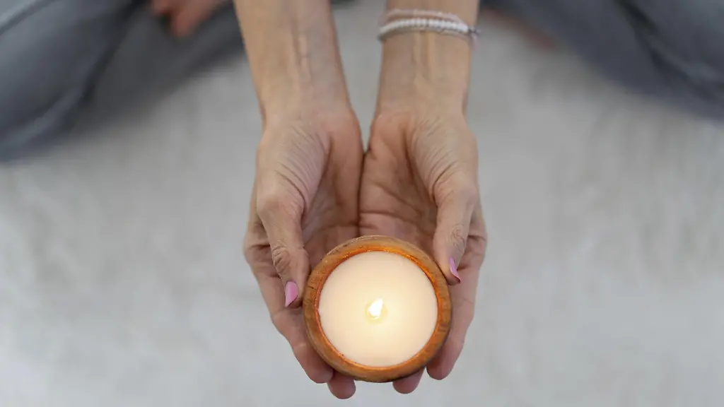 Blick-von-oben-auf-eine-brennende-Kerze-die-von-einer-meditativen-Frau-gehalten-wird-Modellfreigabe-vorhanden