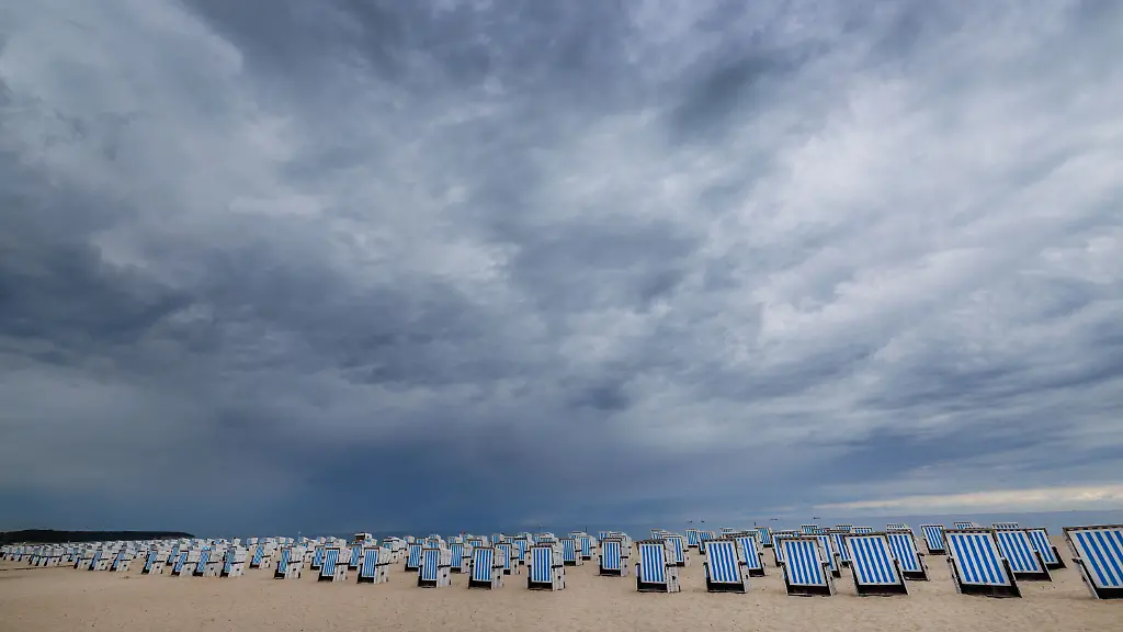 Dunkle-Regenwolken-ziehen-ueber-dem-Ostseestrand-von-Warnemuende-auf