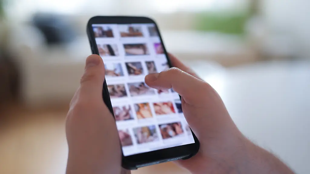 ILLUSTRATION-Ein-junger-Mann-schaut-sich-auf-einem-Smartphone-eine-Porno-Internetseite-an-gestellte-Szene