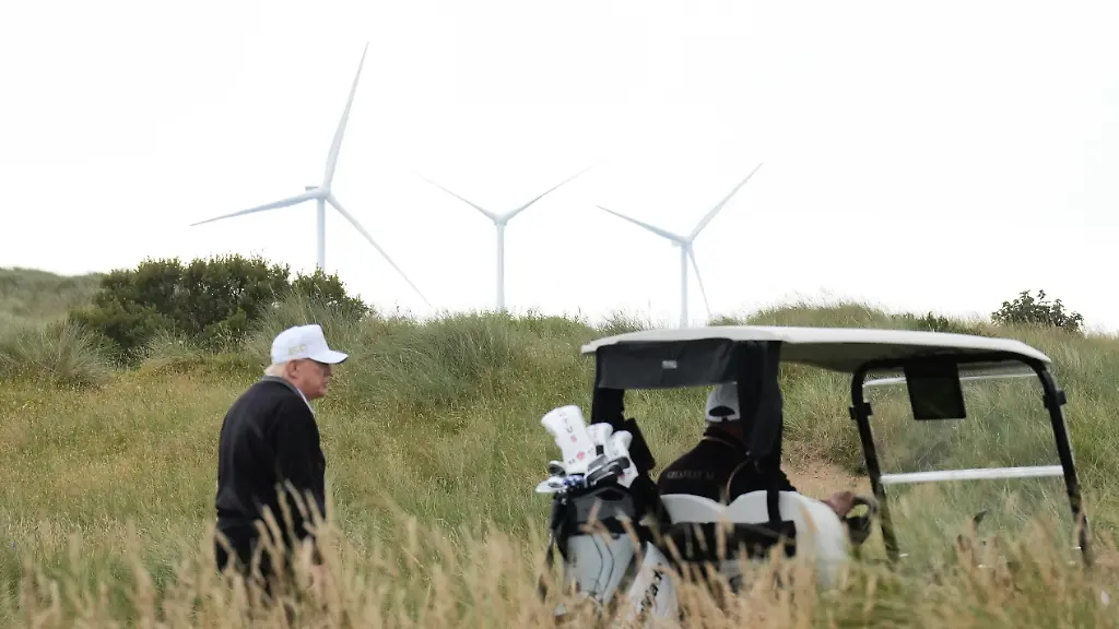 President-Donald-Trump-walks-backdropped-by-wind-turbines-during-an-opening-ceremony-for-the-Trump-International-Golf-Links-golf-course-near-Aberdeen-Scotland-Tuesday-July-29-2025