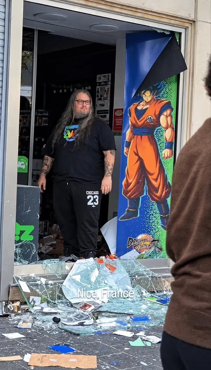Pierre steht neben einem Goku-Aufsteller im beschädigten Eingang einer Micromania-Filiale in Nizza.
